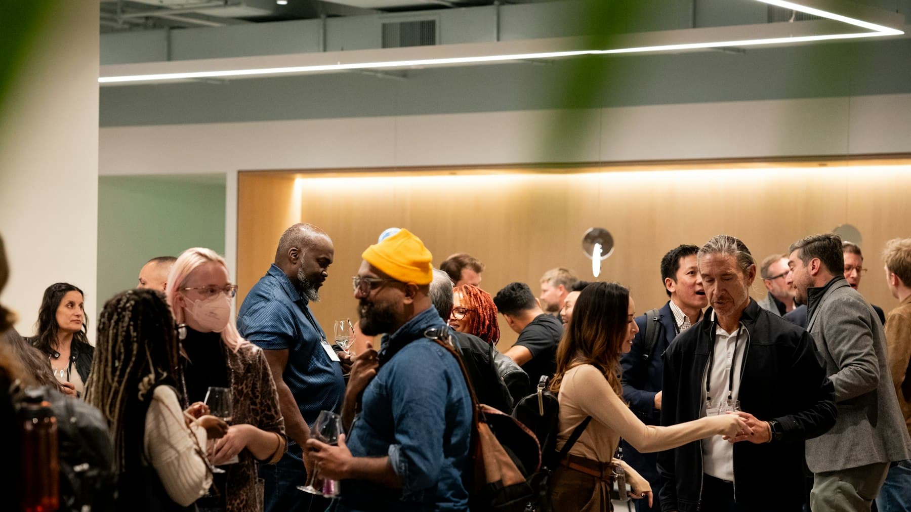 Guests in conversation at an indoor networking reception, wearing lanyards