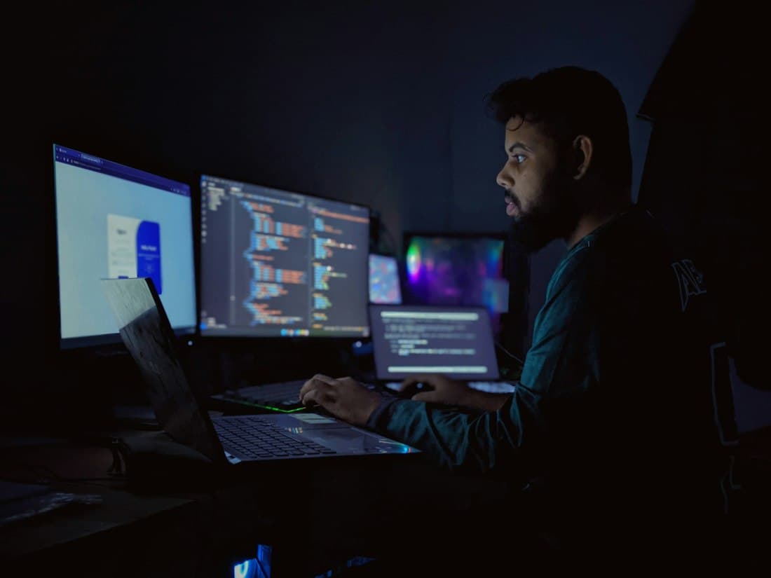 An engineer working at night across three monitors