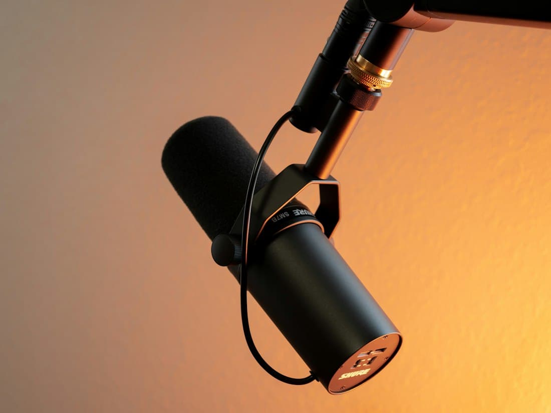 A studio condenser microphone against a warm wall
